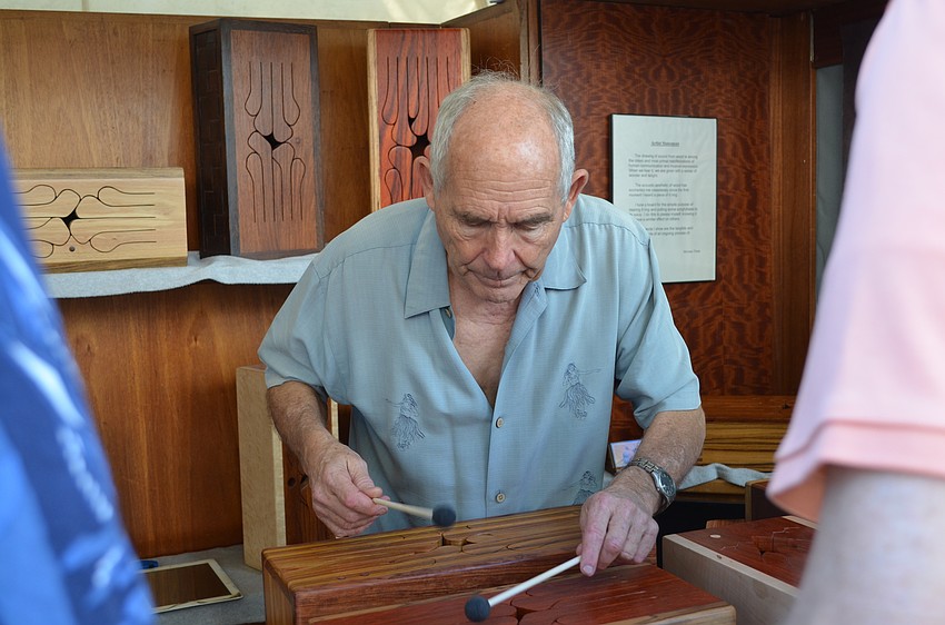 Michael Thiele demonstrates for patrons how to make music with his wooden boxes.
