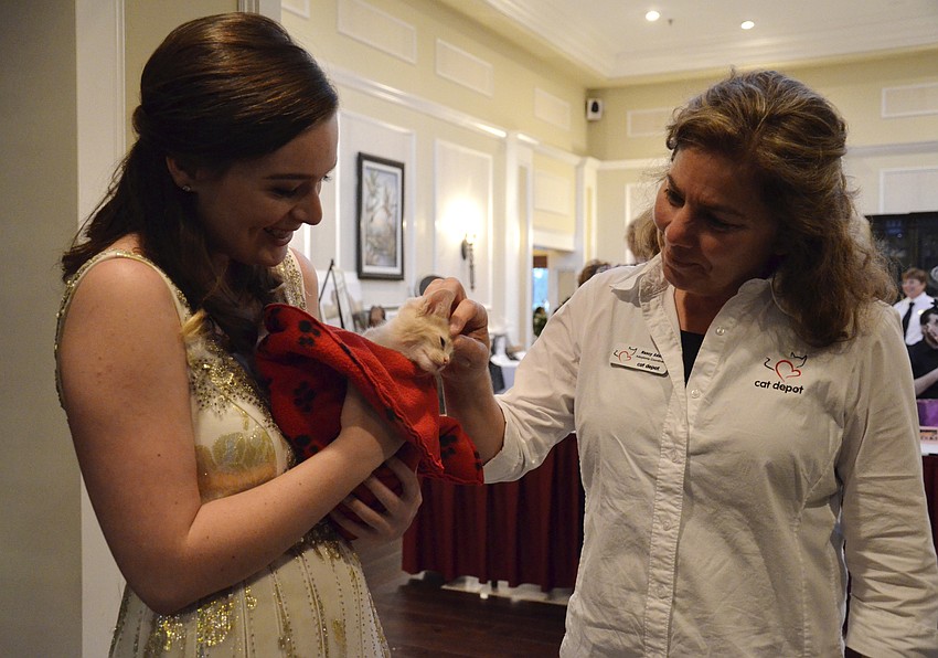 Camden McLean, one of the concert singers, holds Tang from Cat Depot while Nancy Adamo of Cat Depot pets him.