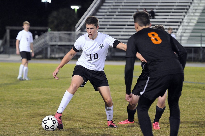 Lakewood Ranch junior defender Tyler Puhalovich attempts to push the ball past Sarasota's Kerrington Anders.