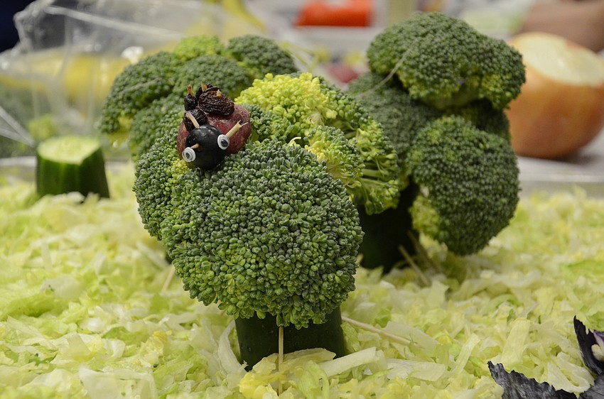 Grapes, raisins and blueberries create a ladybug on top of a broccoli tree in one group's scene, 