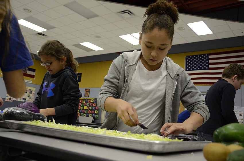 Maribel Arisa sets down purple cabbage leaves as water in the scene.