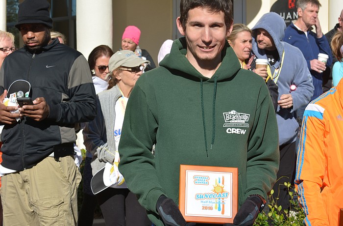 Overall champion Michael Lamb of Bradenton poses with his plaque. Lamb, a University of South Florida student, set a personal best at 1:14.32.