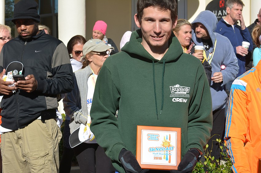 Overall champion Michael Lamb of Bradenton poses with his plaque. Lamb, a University of South Florida student, set a personal best at 1:14.32.