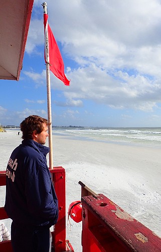 Sarasota County lifeguard Troy Knopp watches over surfers Saturday, during a period of heavy waves. The red flag indicates highly hazardous conditions in the Gulf.