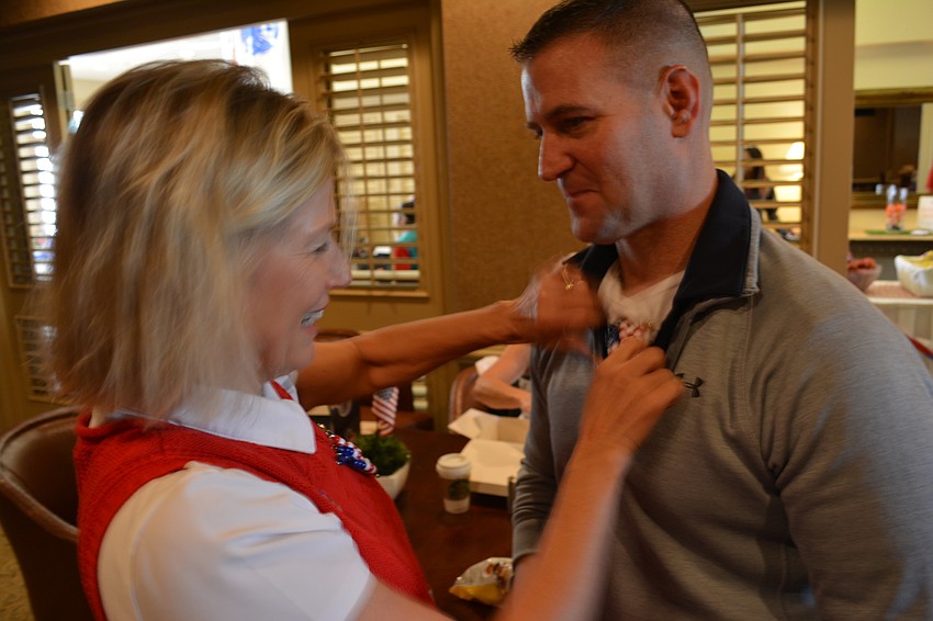 Diane Hennessey, the leader of Girl Scouts Troop 180 out of Braden River Elementary School, attaches one of the patriotic pins made by the troop on Lt. Col. Steve Skelton, who was volunteering at the tournament.