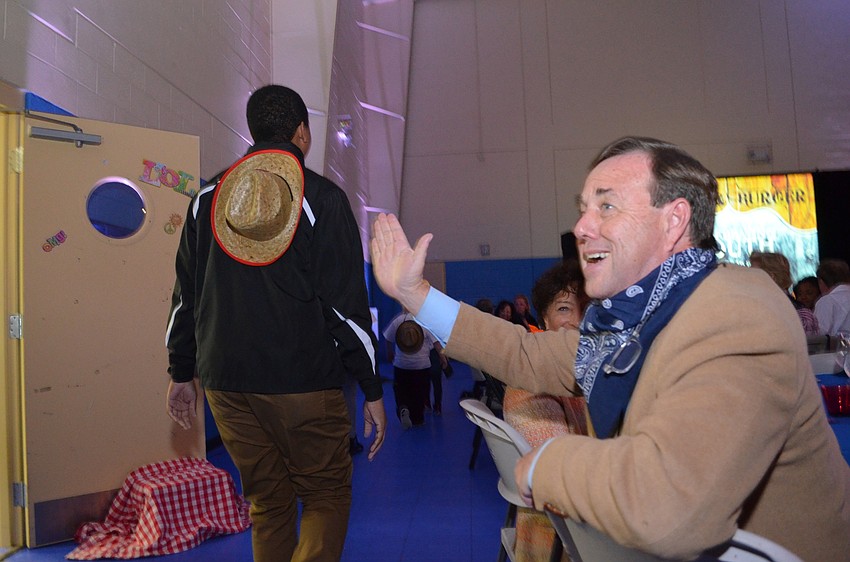 Tom Waters greets members with a high five as they enter the event.