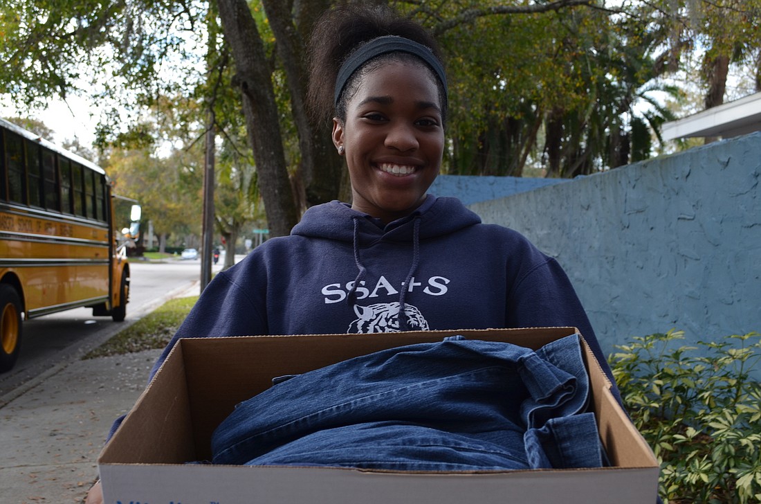 Eighth-grade student Shamyra Wheeler helps carry a box of jeans to be donated. She donated two pairs of jeans from her own closet for the cause.