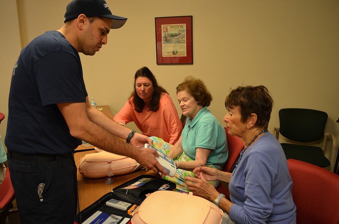 Firefighter/paramedic Jose Rivera  teaches Bayport residents Chris Lake, Arlene Scarlett and Sue Rosen how to use an automatic external defibrillator Feb. 3 at the north fire station.