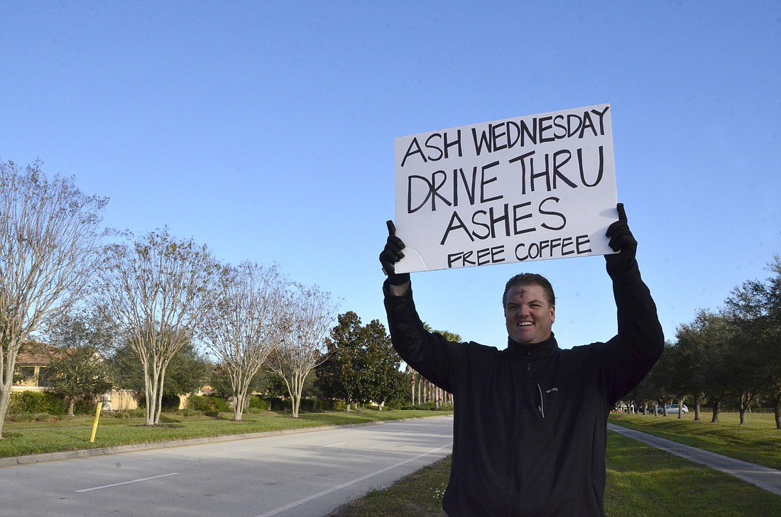 Volunteer Rich Cunningham waves in commuters to get ashes for the holy day.