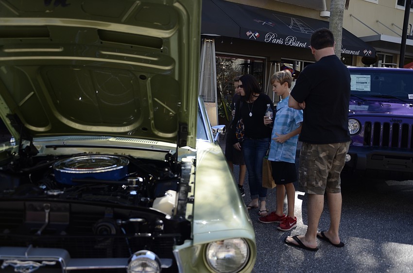 Zack, Mona and Adam Bell and James Beckley of Lakewood Ranch peer into the window of a Ford Mustang.