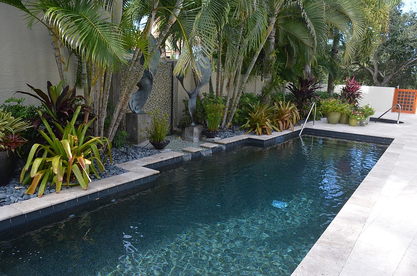 The pool area includes a hot tub and is surrounded by lush greenery.