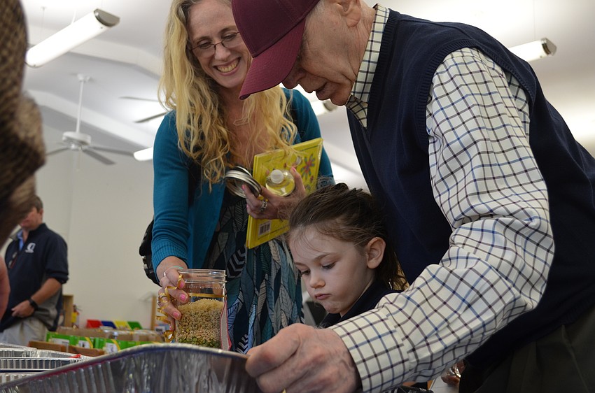 Maxine measures out ingredients to add to the a soup in a jar kit with her mother Lenore Gould and Steve Conviser. Students along with their grandfriends helped put together a soup in a jar kit for sea shell soup.