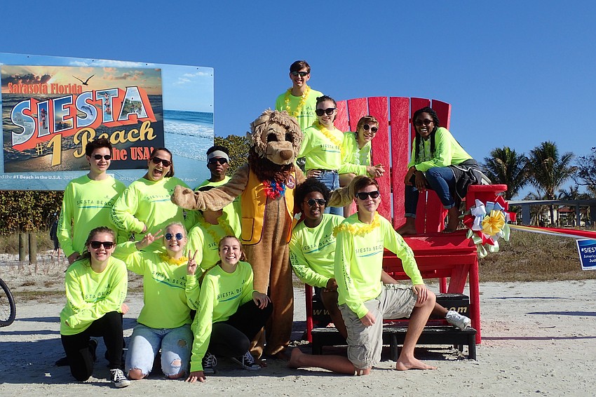 A flash mob of students from Booker High School's visual and performing arts program poses with Lenny the Lions Club Lion