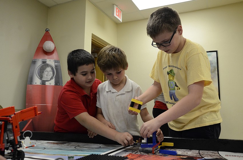 Jett Carotti, Jackson Bennett and Justin Cangro check out the robotics equipment. Cangro helped program the robot to knock over a Lego tower.