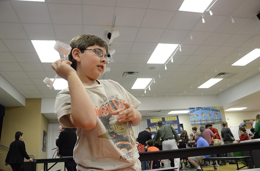 Jack Phillips tests out an alternative paper airplane made with a straw and paper rings.