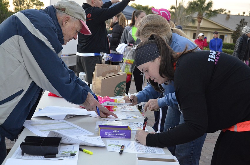 Volunteer Doug Schiller helps Nicole Kurtz of Lakewood Ranch sign in.