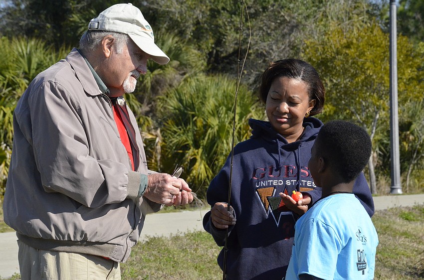 Angler's Club member Virl Mullin shows Jennifer and Josiah Minton of East Bradenton a different kind of bait to use to try and catch a fish.