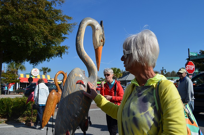 Debbie Gerardi inspects the blue heron wooden sculpture by artist Ademir Borges.