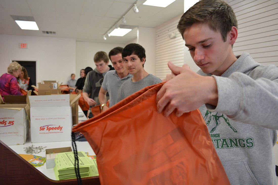 Nick Rego stuffs a participant bag for the Take Stock in Children 10K/5K.