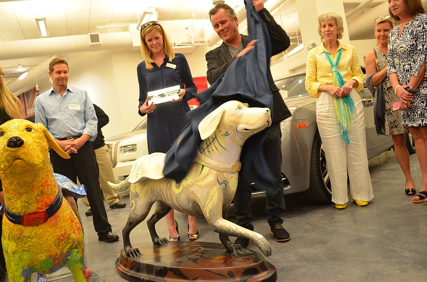 Artists and sculptor Scott Joseph Moor lifts the sheet to reveal the statue named 