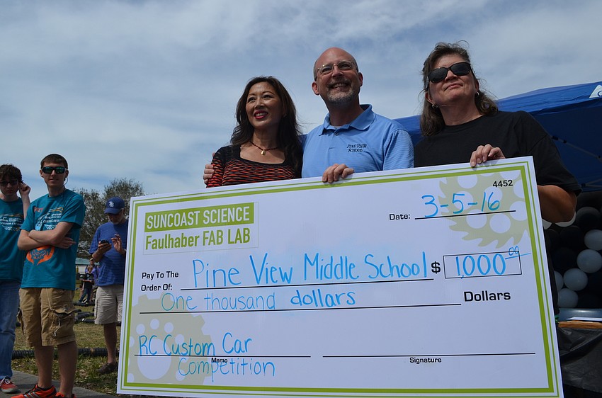 Pine View School Principal Stephen Covert and seventh grade science teacher Hali Flahavan accept a check for $1,000 from the Suncoast Science Center.