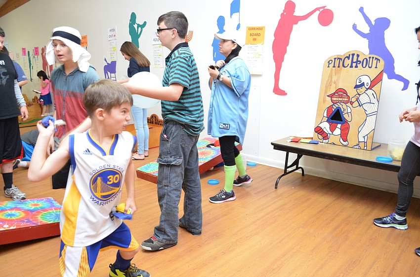 Gabe Yamada gives his best pitch on a carnival game at the Temple Emanu-El Purim Pandemonium.