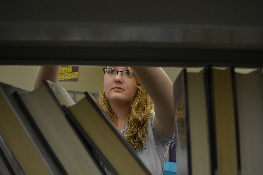Braden River High School student Taylor Nelson, 16, returns books to their shelves for community service hours.