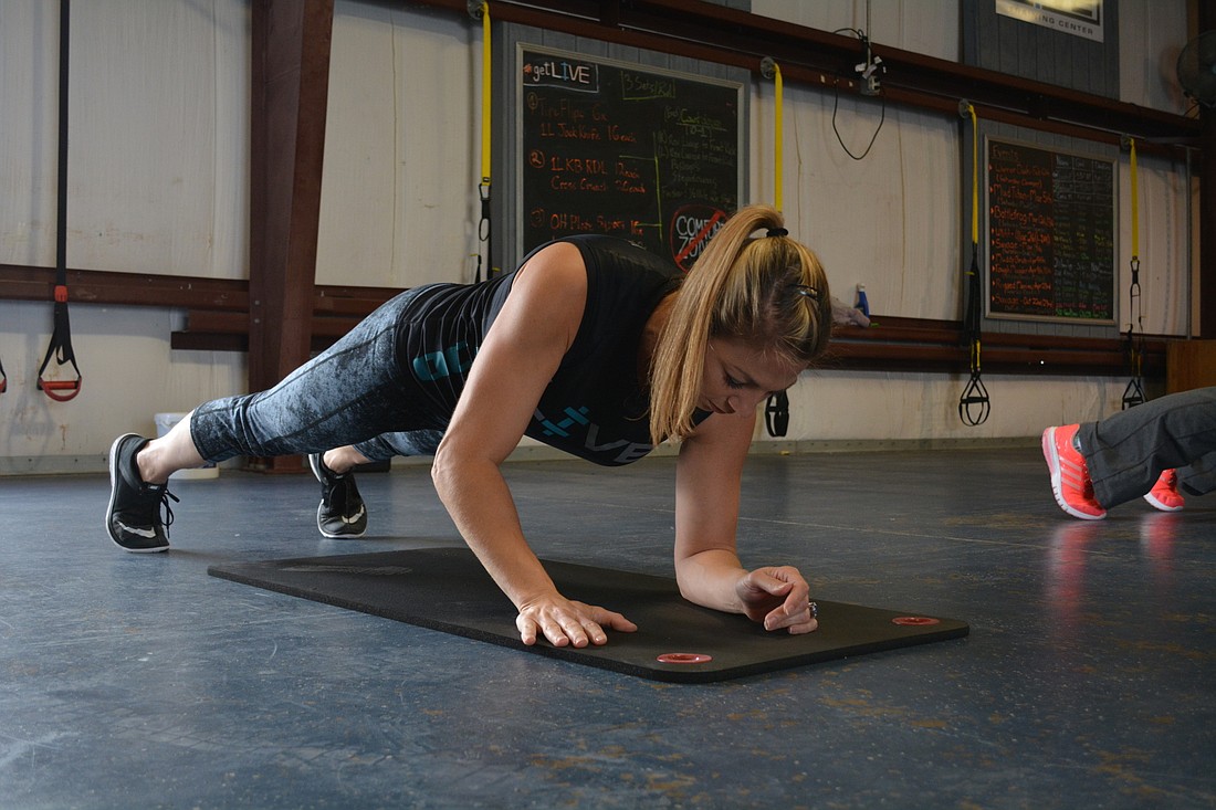Cintia Manasseh-Caputo does plank exercises during a fitness class at LIVE Training Center, in Palmetto, where she also can practice Ninja Warrior obstacles.