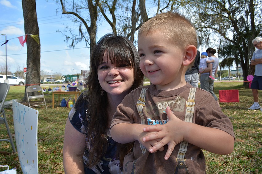 Nicole Parsley, a teacher at the school, helps her son, David, and other children with the duck pond game.