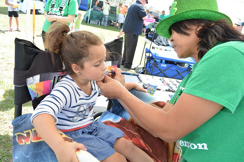 Maya Petricca has Akiko Campbell paint a rainbow and a pot of gold on her cheek.
