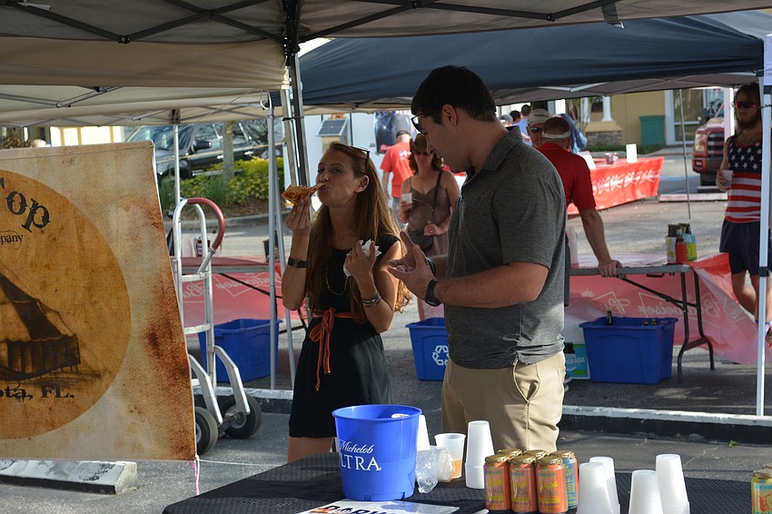 Kristin Martin takes a break from handing out craft beers for Motorworks Brewing to enjoy a slice of Wolf's Head pizza with Matt Cornelius of Darwin Brewery.