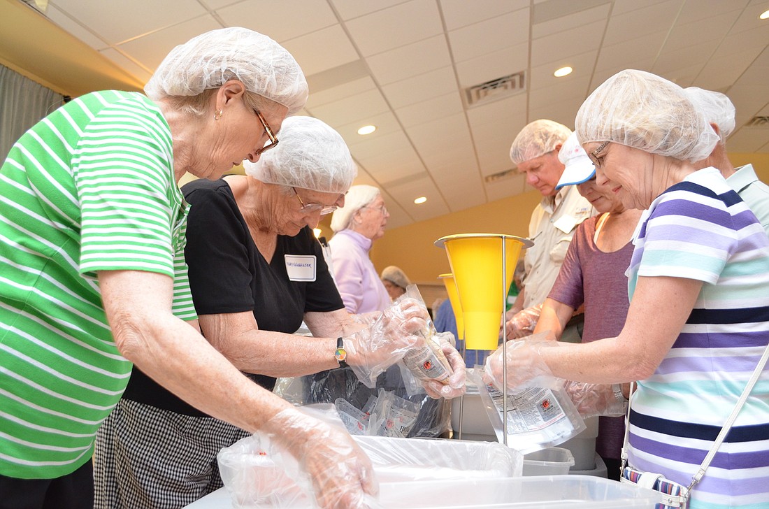 Jackie Crews, Mary Neauhauser and Chris Parlett measure scoops of rice, dehydrated vegetables and soy flour.