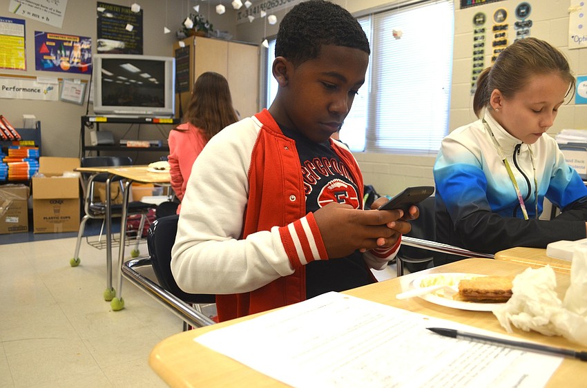 Bryson Robertson, a Nolan student, uses a calculator on his phone to solve an equation, while snacking on pie.