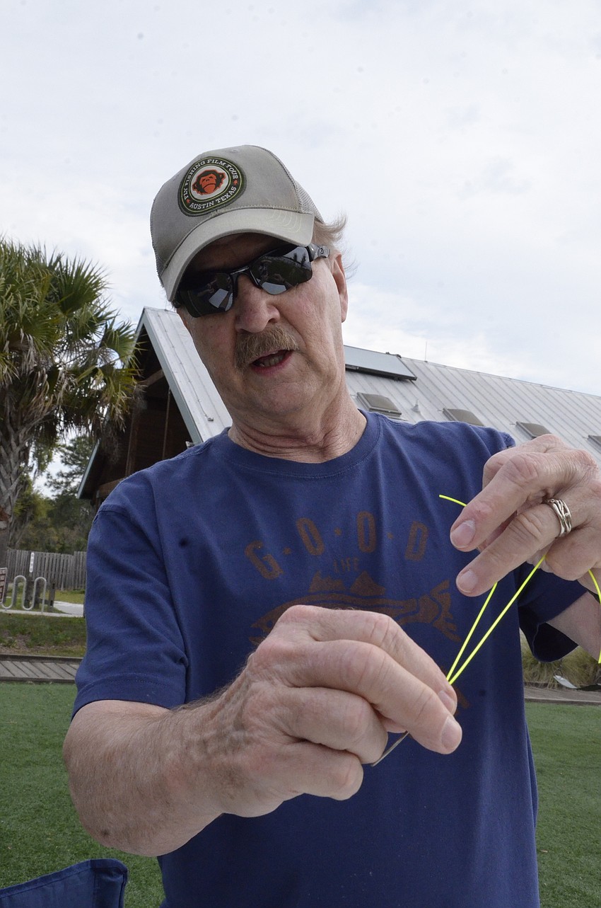 Ken Kenzie, a volunteer, shows visitors how to tie a knot on a hook.