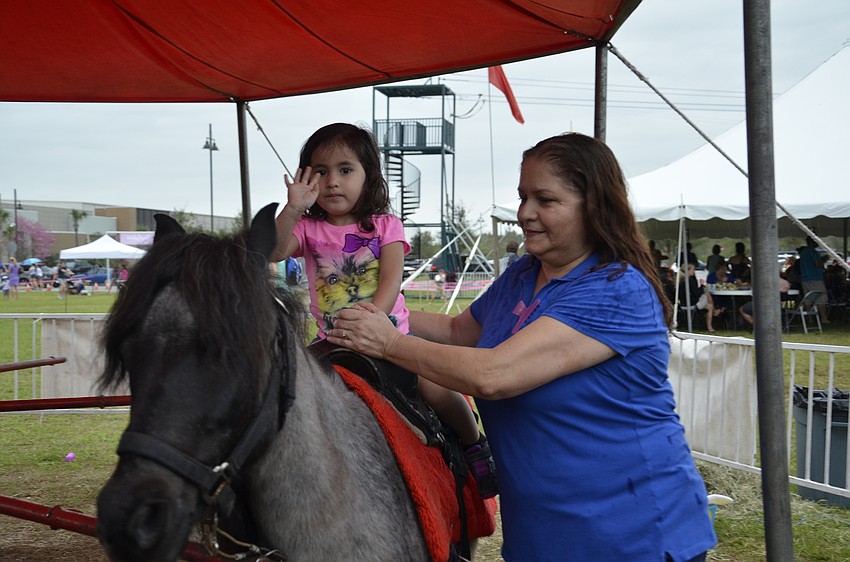 Evianna Oyola gets a ride with a little help from grandmother Yoly Sanchez of Palmetto.