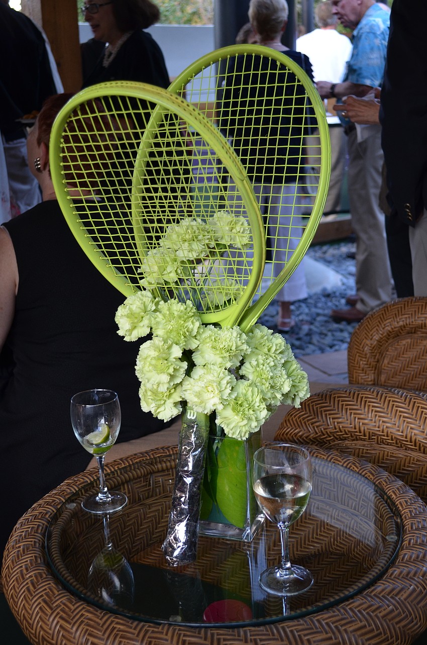 Flowers arranged with tennis rackets sit in the cocktail area by the tennis courts at the Twitchell House.