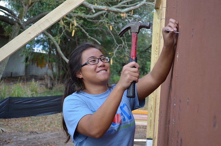 Kate Lam hammers in a nail to the side of the Habitat for Humanity house.