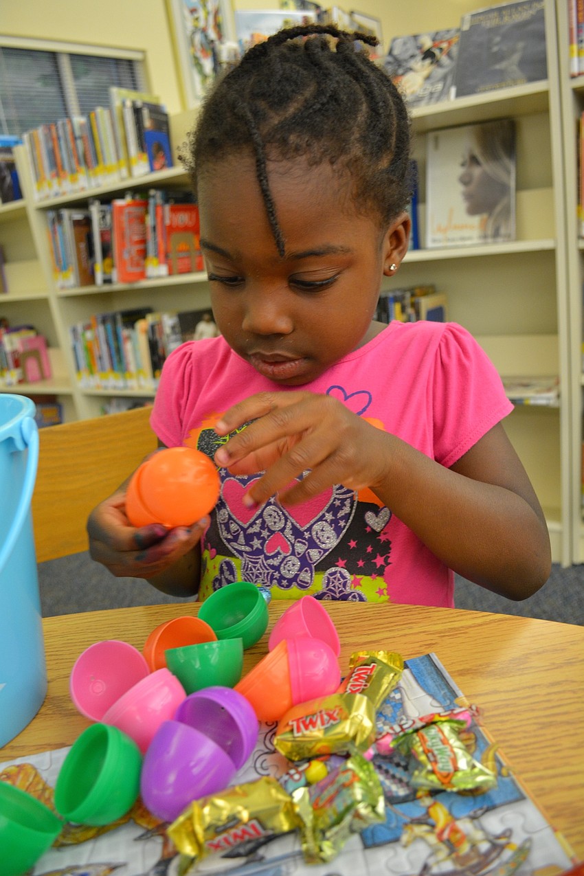 Four-year-old Taylin Stilley, of Heritage Harbour, cracks open her eggs in search of treats.