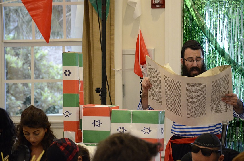 Rabbi Mendy Bukiet reads from the Megillah, or Scroll of Ester, which recounts the salvation of the Jewish people from a Persian vizier.