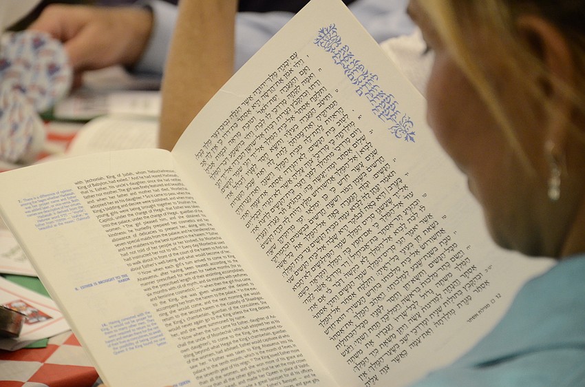 Ester Cohen reads along in the Megillah while Rabbi Mendy Bukiet reads aloud.