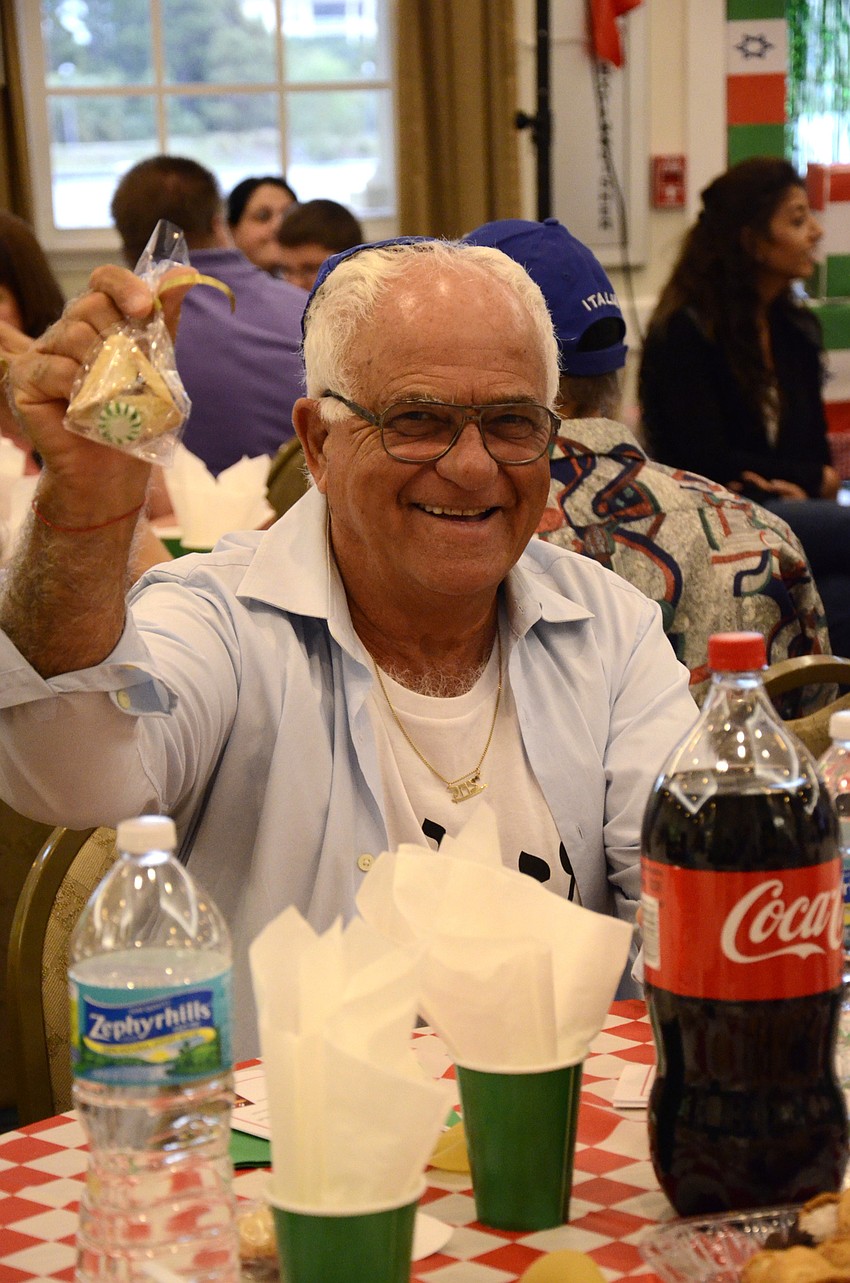 Isaac Abitbol holds up a pastry for the traditional giving of food to his neighbor at the table.