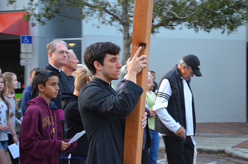 Christoph Moe leads the group down Main Street holding the wooden cross.