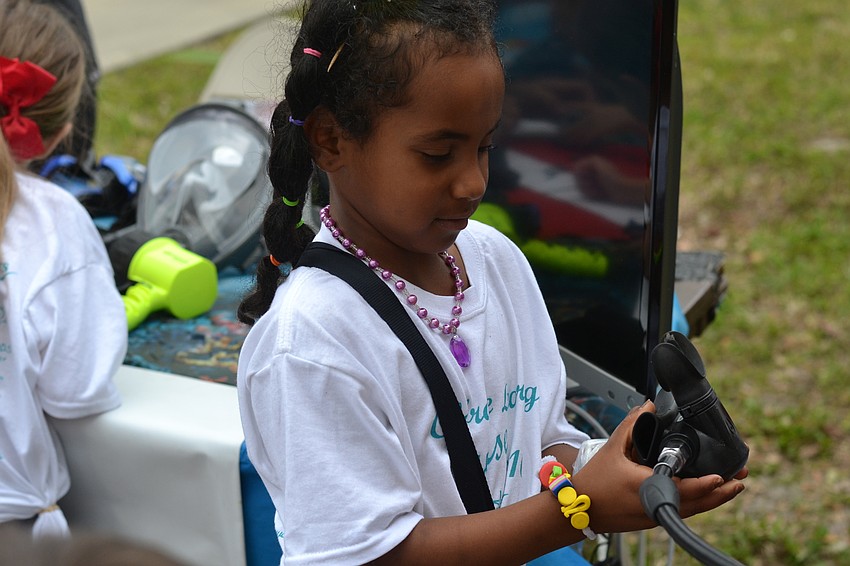 Zahara Sir tests the mouthpiece on a scuba tank.