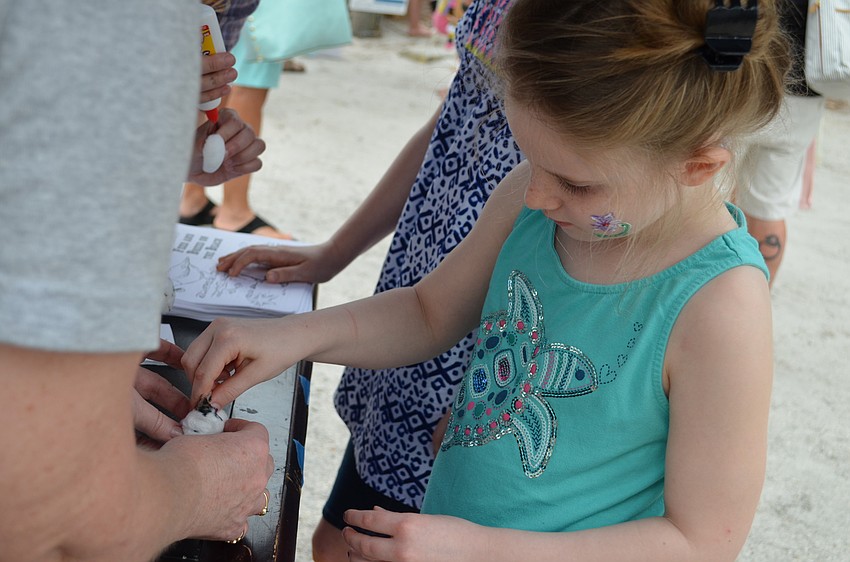 Caroline Green adds the sunflower seed beak to a snowy plover craft.