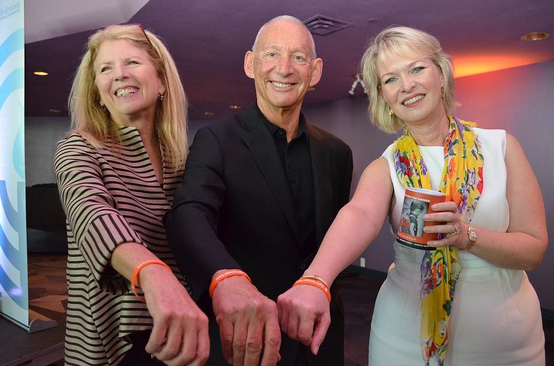 All Faiths Food Bank CEO Sandra Frank with Keith Monda, Feeding America board member and Gulf Coast Community Foundation Senior Vice President for Philanthropy Veronica Brady show off their orange wrist bands for the Campaign Against Summer Hunger.