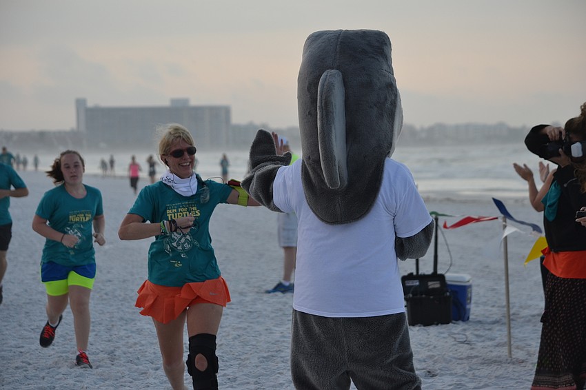Jenah Victor give Gilly the shark a high-five as she crosses the finish line for the one-mile fun run/walk.