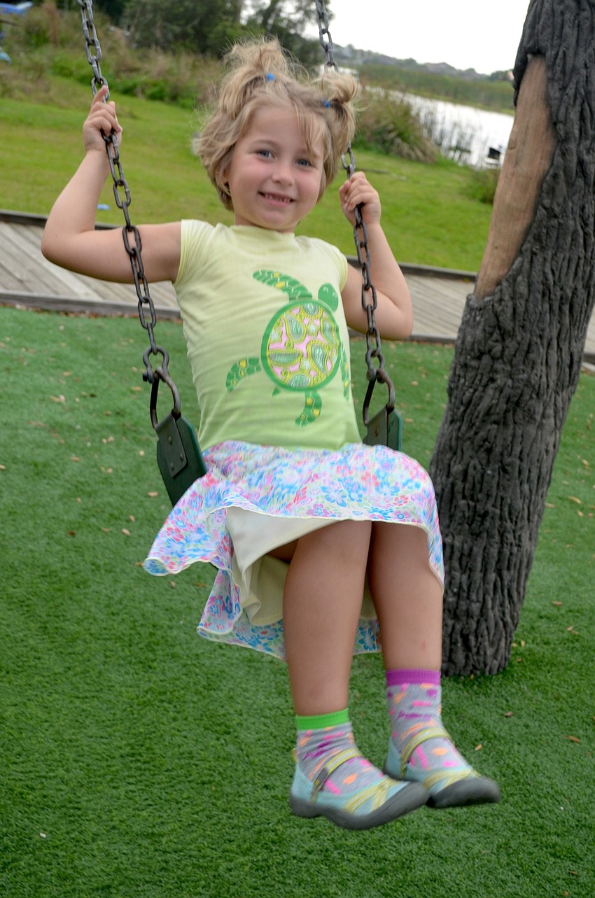Six-year-old Natalie Wojs, of Bradenton, tests of the swing set on the playground at Jiggs Landing.