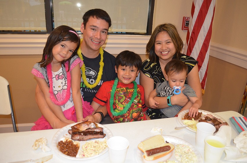 The Hopkins family — Kaia, Nick, Kaylor, Nikki and Kaden — enjoy barbecue food while sporting Hawaiian leis.