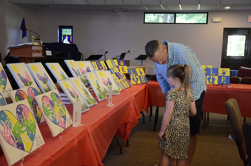 Michael Truax and his daughter, Lily, check out the paintings created by the preschool classes. The paintings featured four different designs that all used hand and finger shapes.