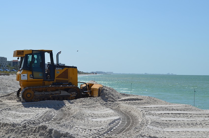 Contractor Alberto Benavides spreads the newly placed sand on Longboat Key’s shoreline Wednesday.